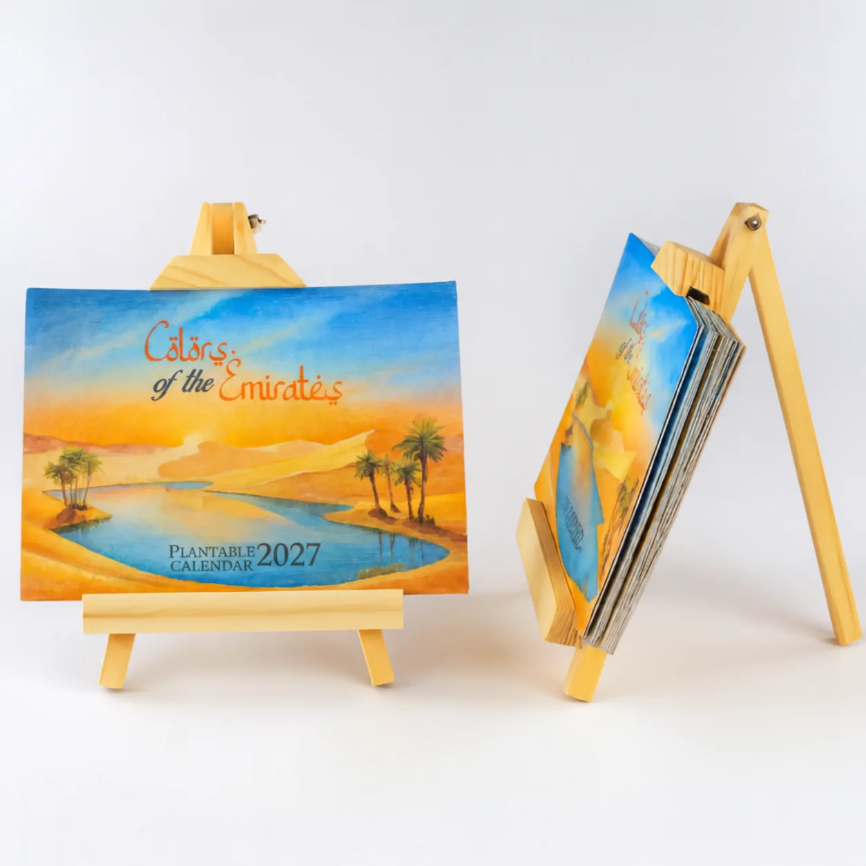 BG62 Colors of the Emirates 2027 calendar cover on a wooden A-frame easel, with a second easel holding the card stack side-on (year digitally updated from the 2026 photograph)