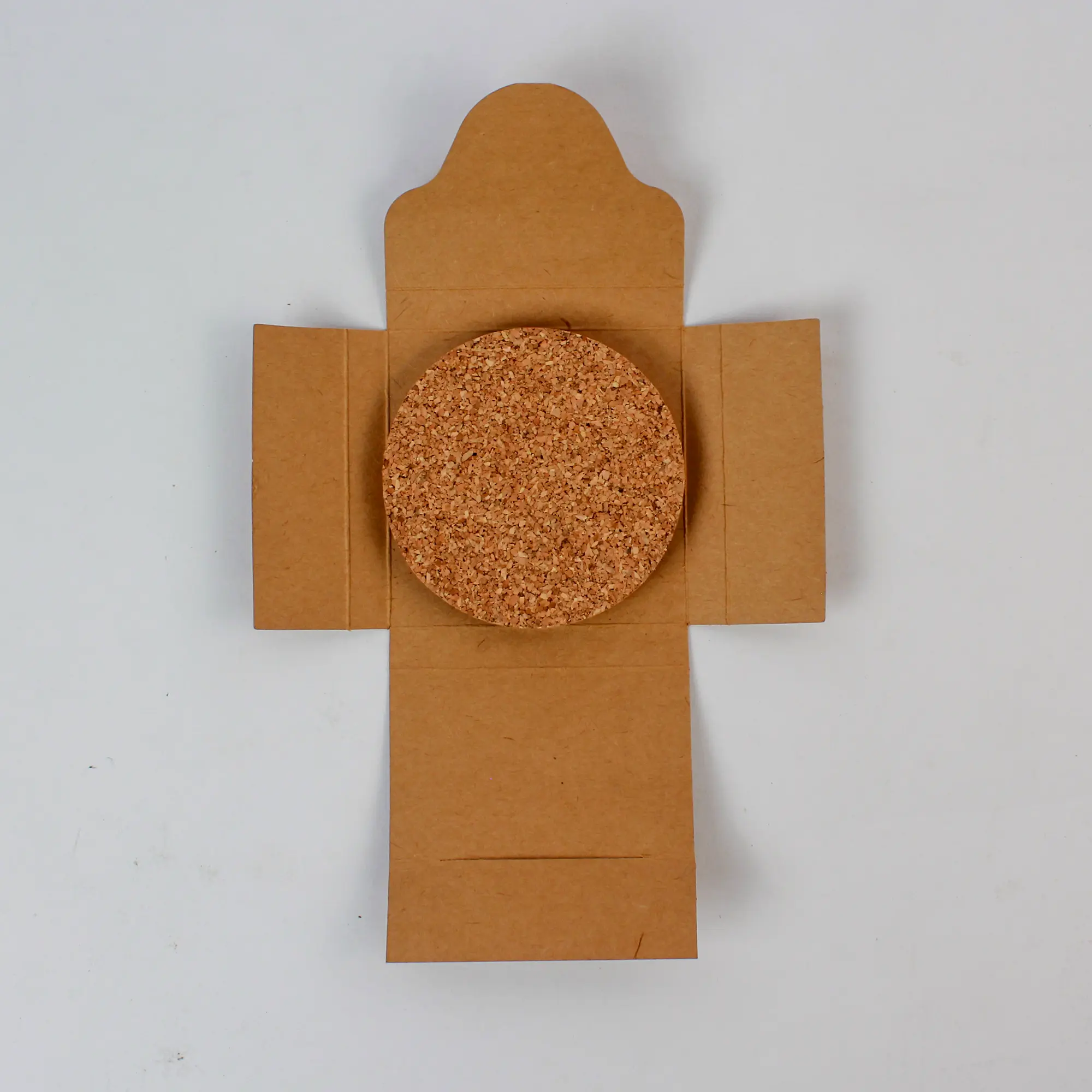 One cork coaster placed on an unfolded kraft sleeve showing the simple pack format
