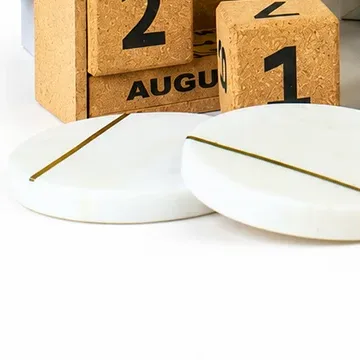 Two round white marble coasters with brass inlay lines