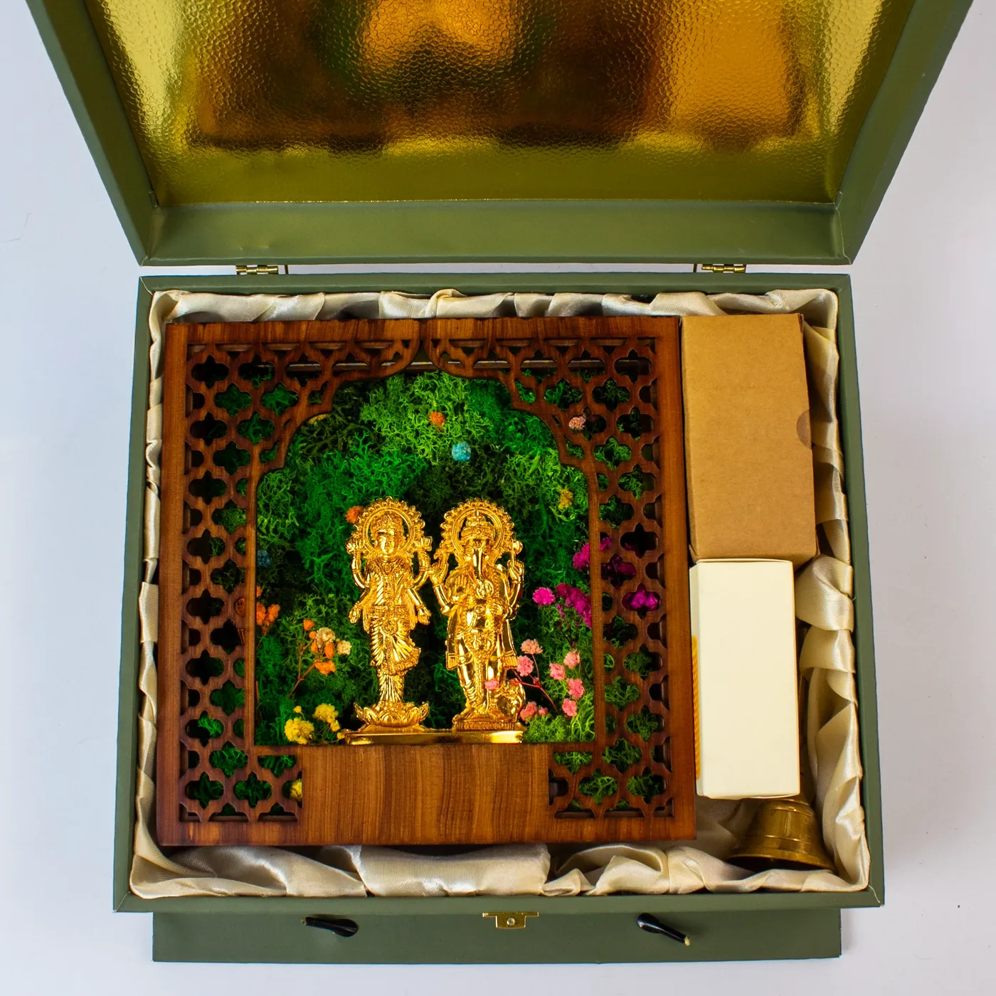 The mandir, the adapter box, the candle box and the ghanti on the ivory satin bed of the open chest
