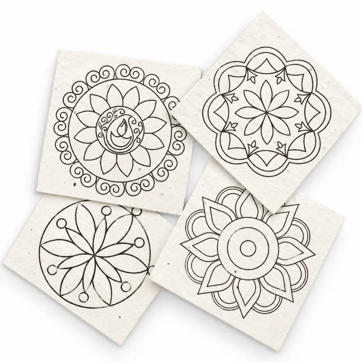 Close view of the four seed-paper rangoli cards, showing the texture of the paper