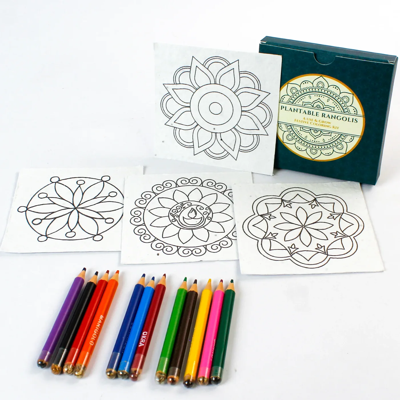 The twelve mini colour pencils of the Rangoli Colour Box in three groups, with the box and four cards