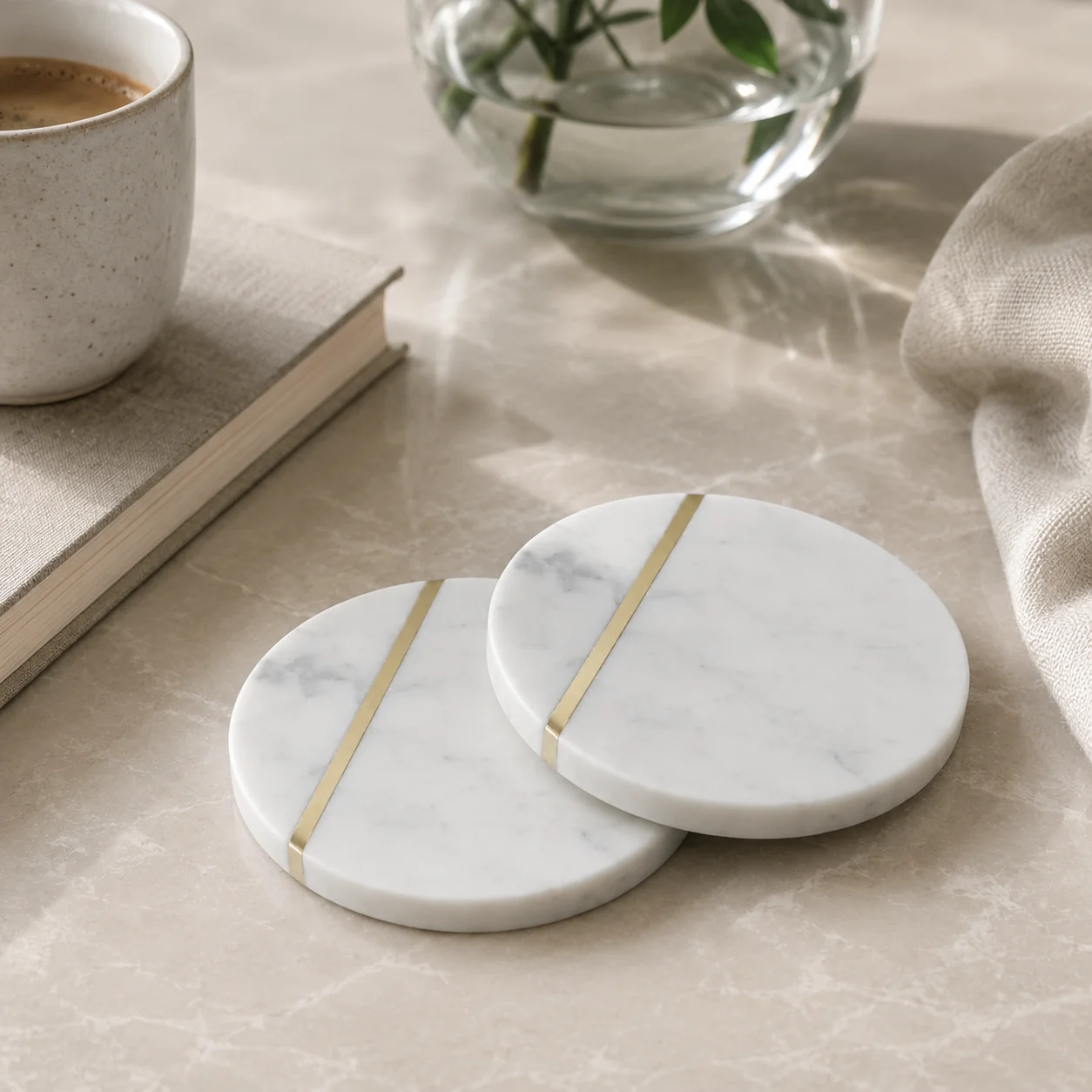 Two round marble coasters with diagonal brass inlay on a table