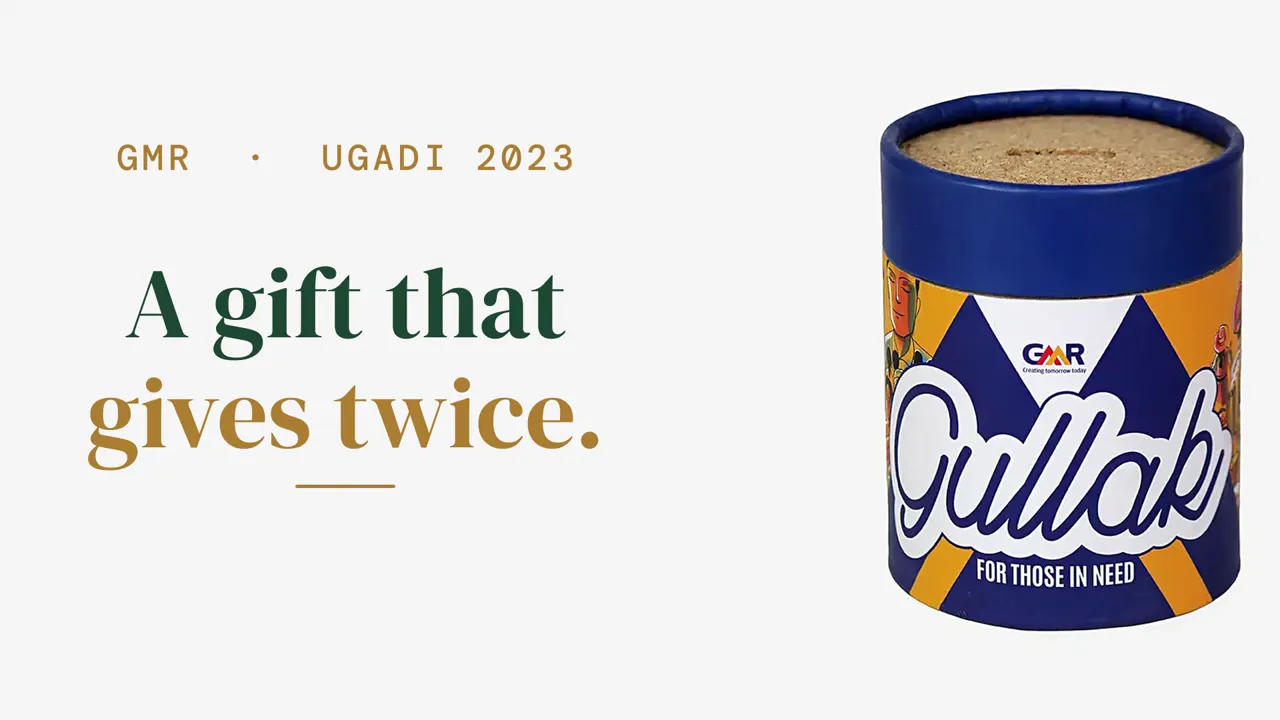 The GMR Gullak: a blue-topped paper-tube coin bank with an illustrated orange wrap, beside the words A gift that gives twice