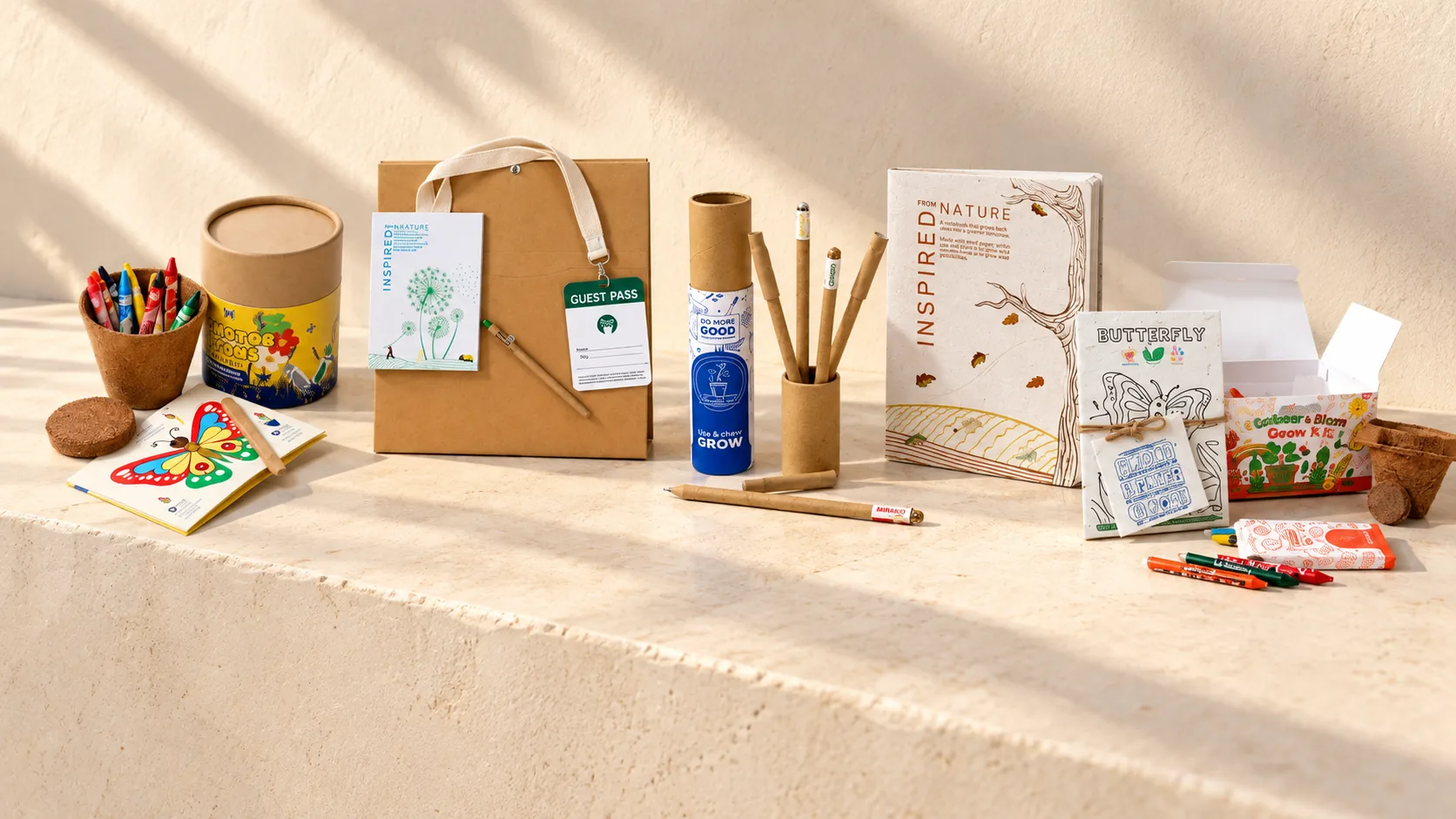 Five plantable gifts on a stone ledge: a butterfly craft kit, a handover kit with a guest pass, a plantable pen set, a seed-paper diary and a colour and bloom grow kit