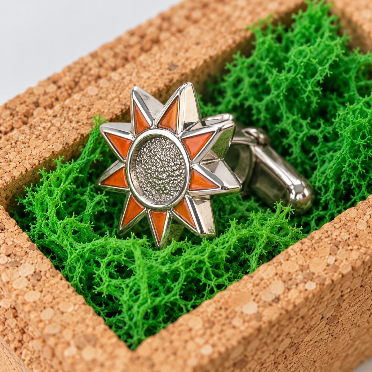Close-up of a sunburst cufflink against preserved moss and the cork edge