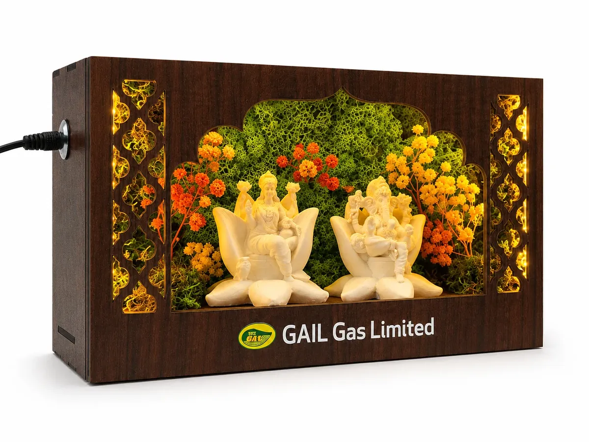 A lit carved frame with Lakshmi and Ganesh figures among moss and flowers, with the client’s mark