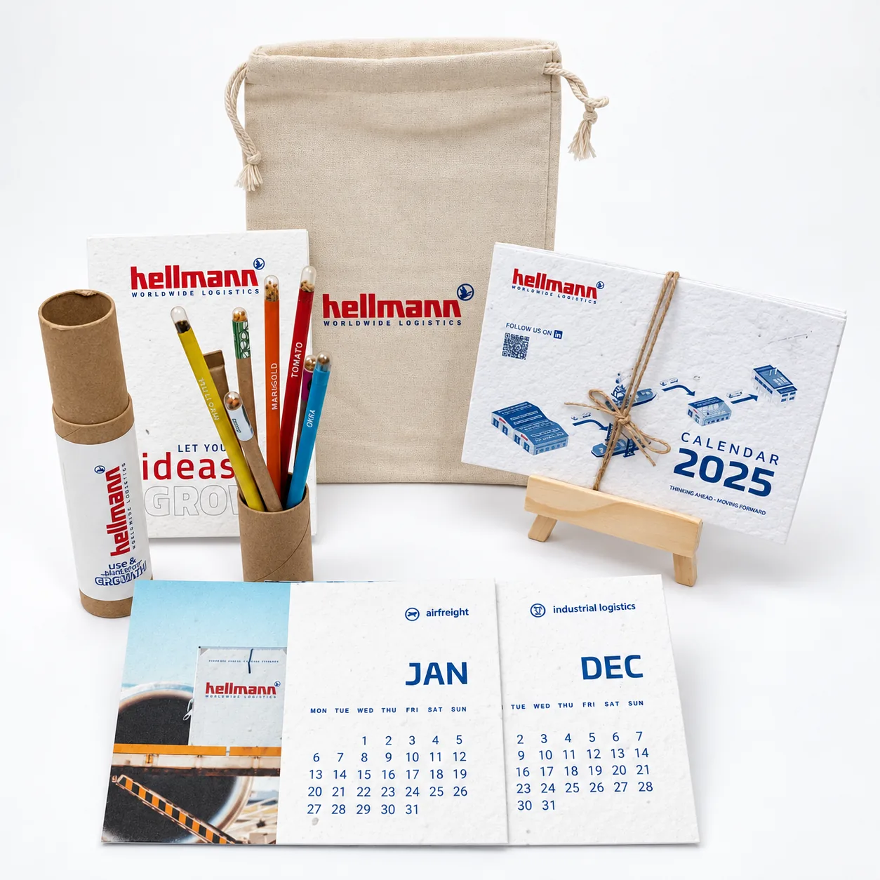 A plantable 2025 desk calendar on a wooden easel with the client’s photographs, a cotton bag, a seed-paper notebook, a kraft tube of seed pencils and loose month cards for January and December
