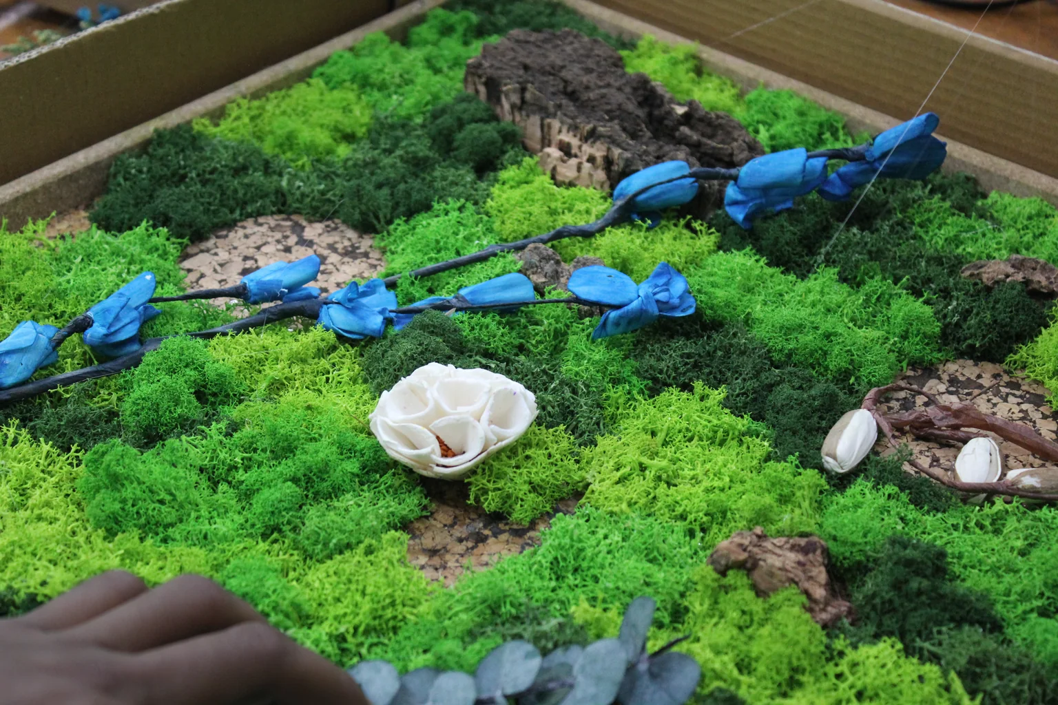 Blue dried flowers and cork set into moss
