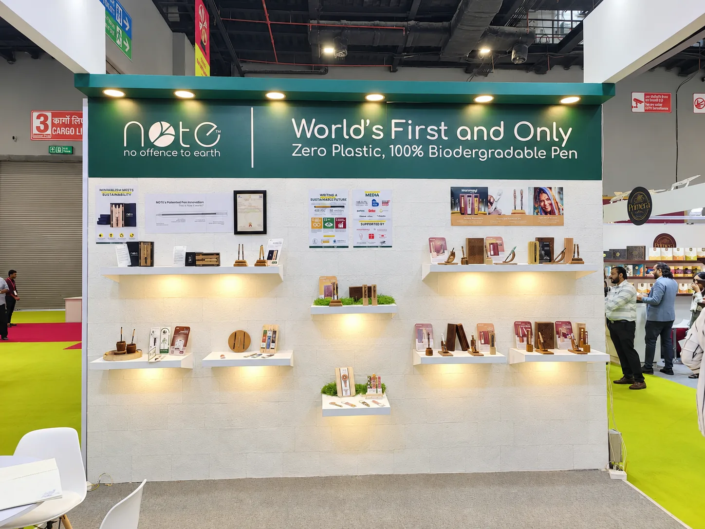 The NOTE stall with a white wall of lit shelves under the sign World’s First and Only, Zero Plastic, 100% Biodegradable Pen
