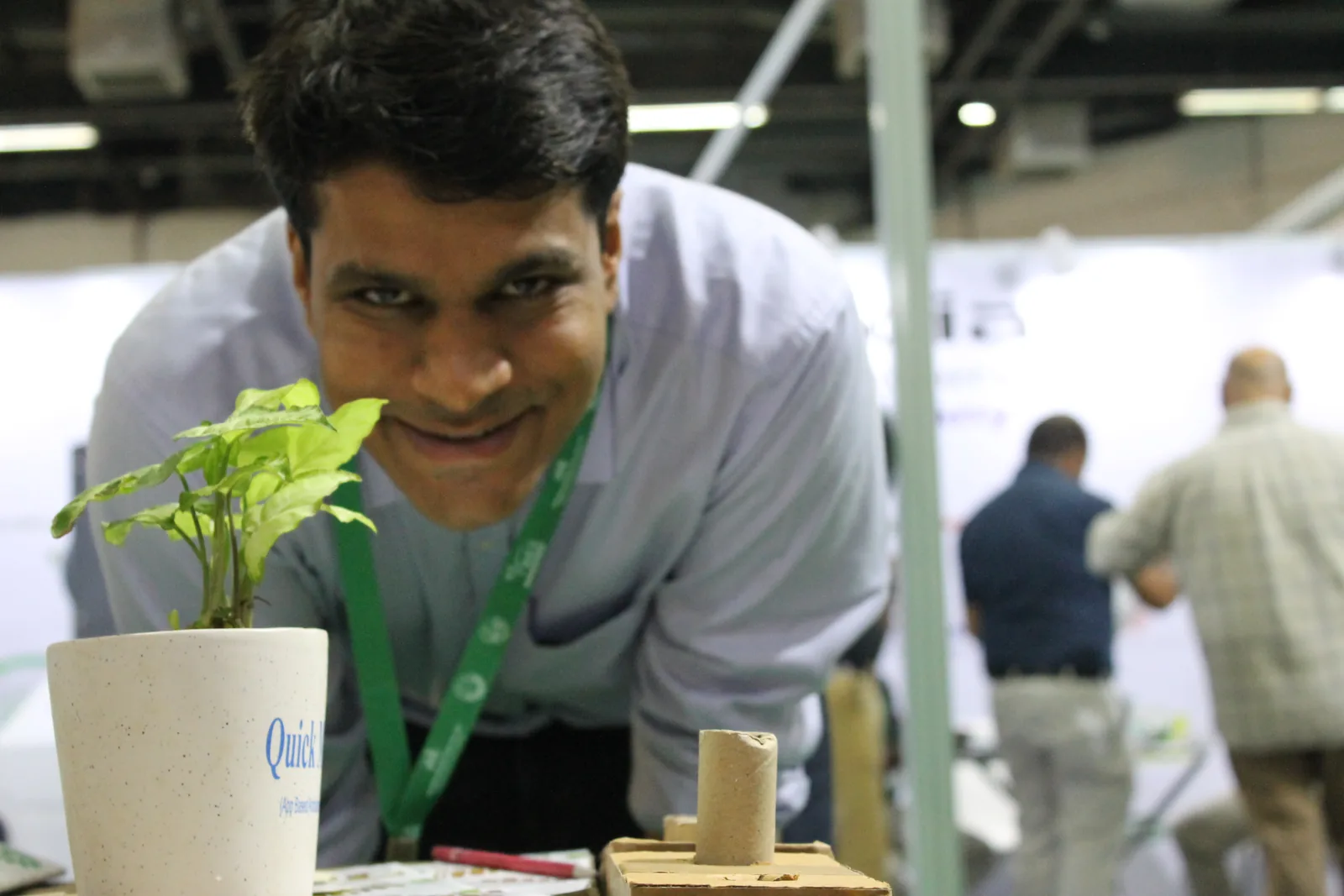 A team member smiling over a small plant in a cream pot on a desk
