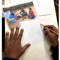 A hand sketching a design in pencil beside a photograph