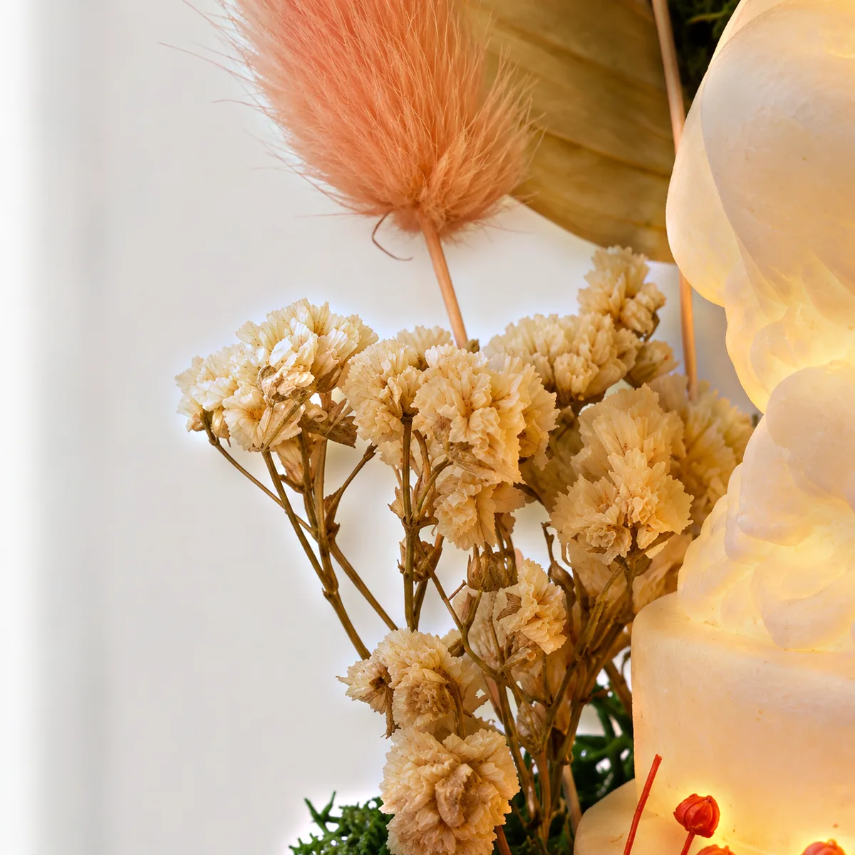 Close-up of a cluster of small cream preserved flowers and a pink grass head