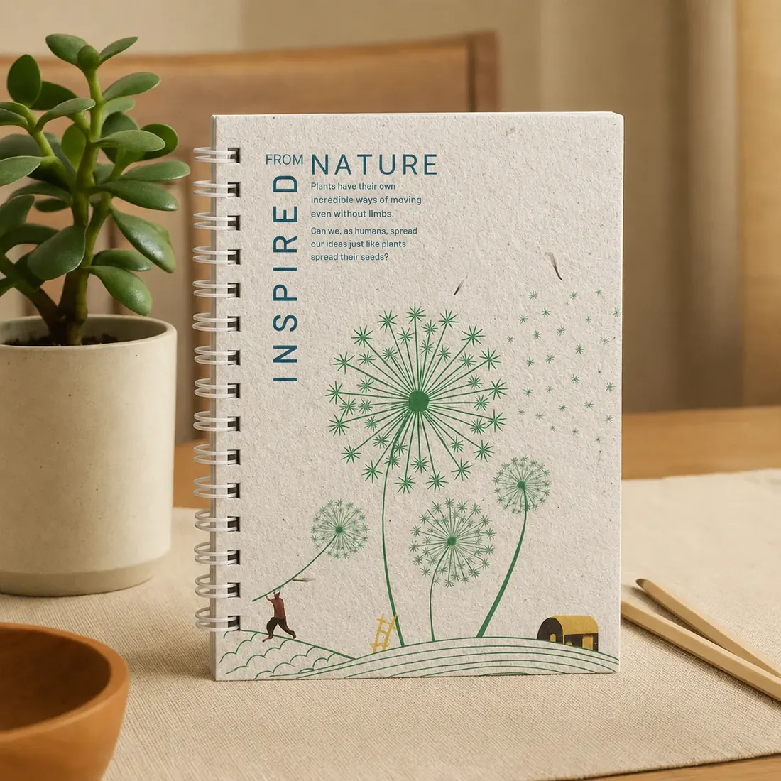 Plantable notebook displayed upright on a desk beside a potted plant