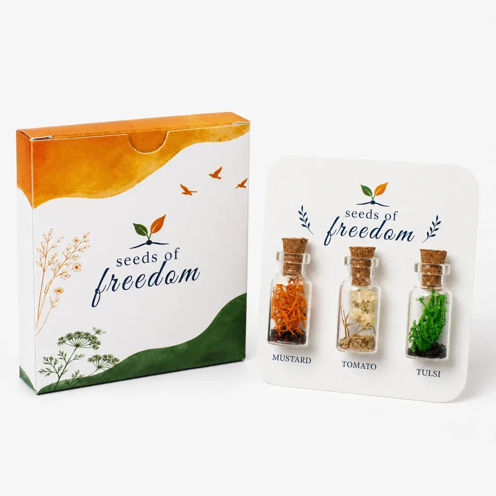 Three Seeds of Freedom glass bottles containing mustard, tomato and tulsi seeds in a tricolour arrangement