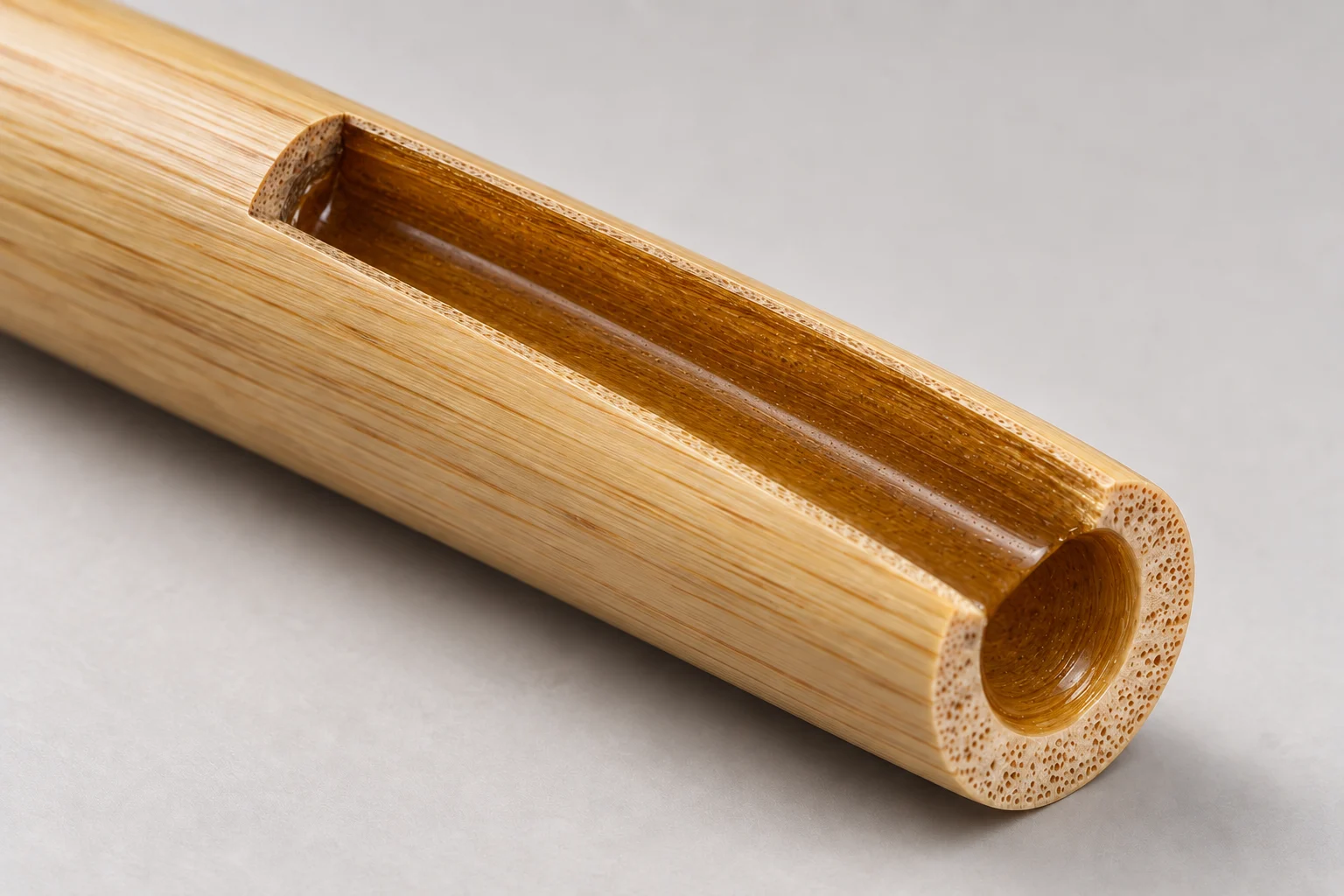 Concept cutaway of the same hollow bamboo barrel, now lined with an amber coating bonded to its inner surface.